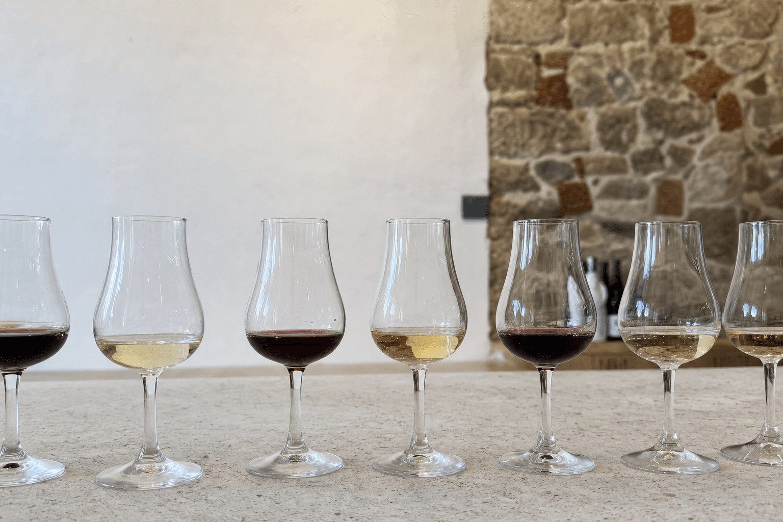Varias copas catavinos ISO normalizadas en fila con vino tinto y blanco sobre un mantel claro