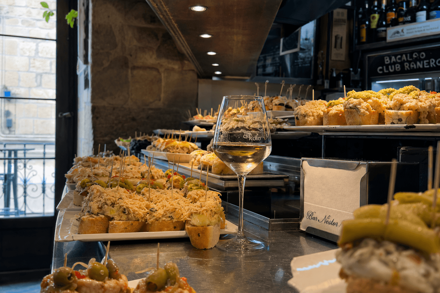 Barra de pintxos vascos con bacalao, txangurro y una copa de txakoli