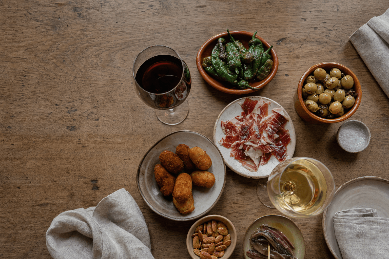 Mesa con varios platos y copas de vino tinto y blanco para maridaje