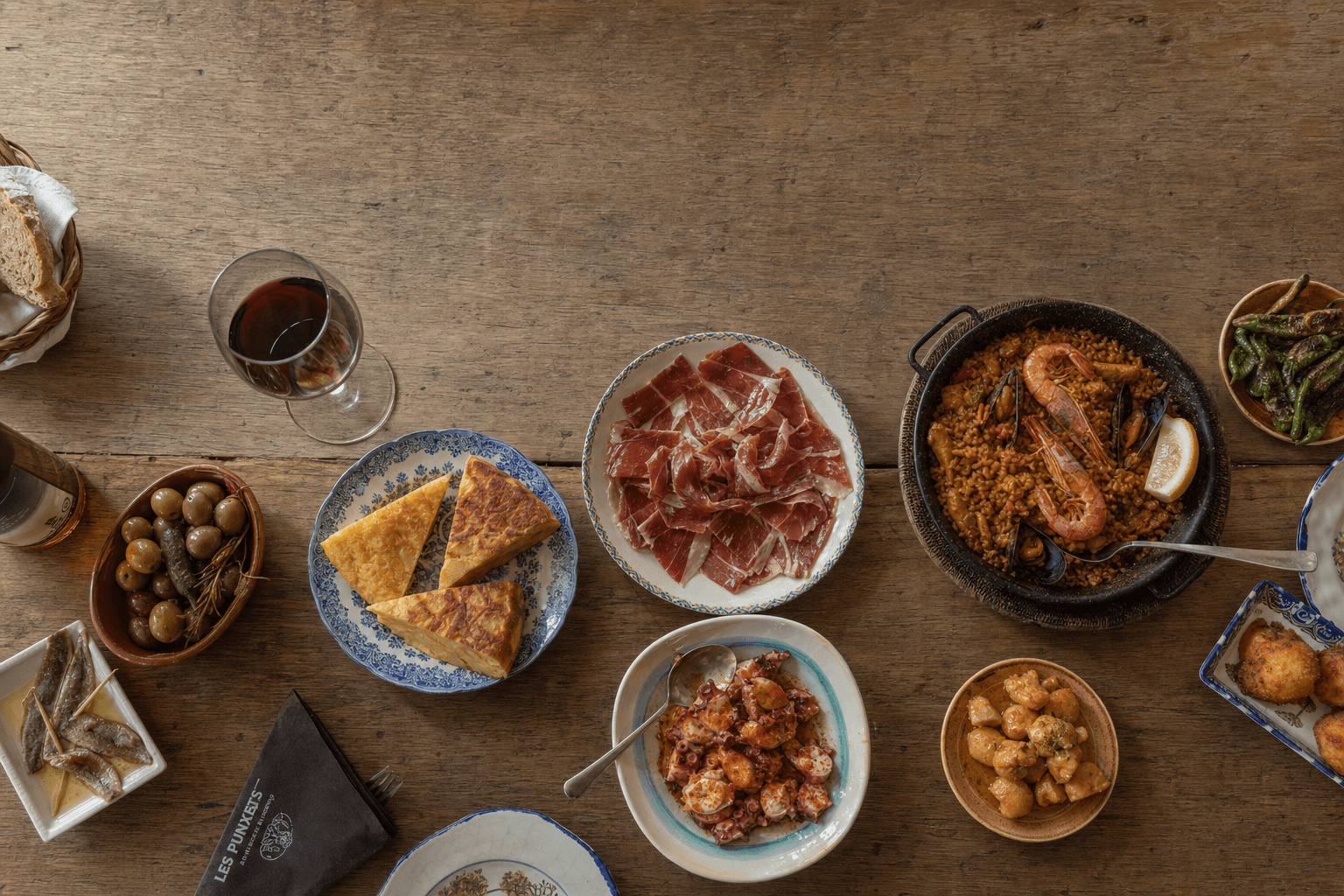 Mesa española con tortilla, jamón, paella, pulpo y una copa de vino tinto